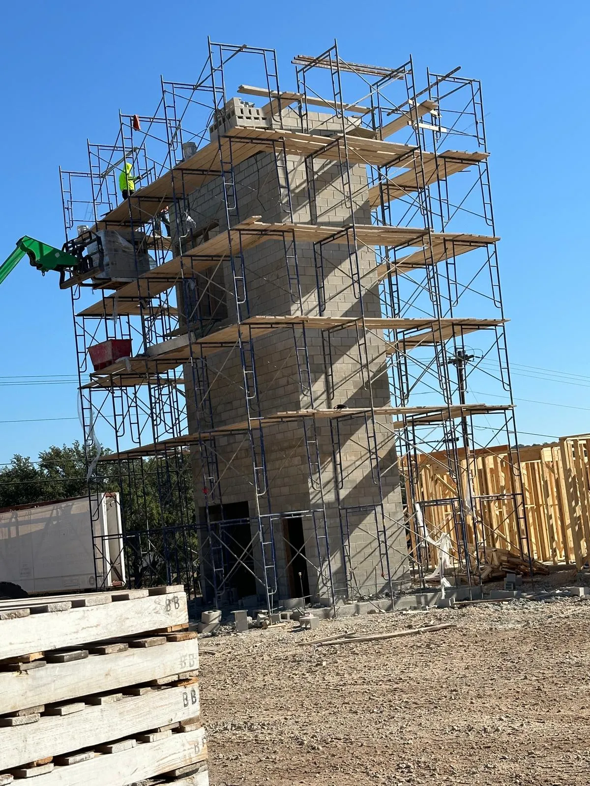 CMU elevator tower in scaffolding against a blue sky